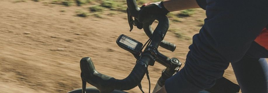 Close-up van een gemonteerde Wahoo ELEMNT Roam op de racefiets over zandpad