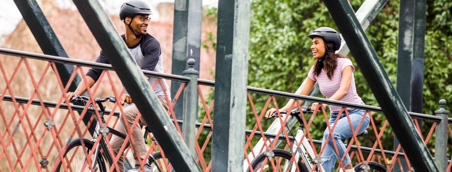 Twee mensen op fietsen met een WaveCel helm op rijdend over een brug met groene en rode kleuren