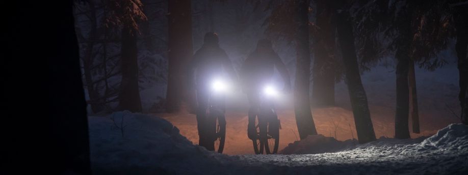 Twee fietsers in een donker bos met felle voorlichten