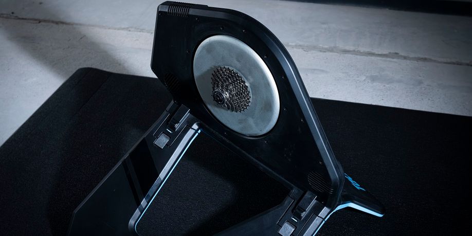 Close-up van de Tacx Neo 2T fietstrainer op een zwarte Tacx trainermat en betonnen vloer