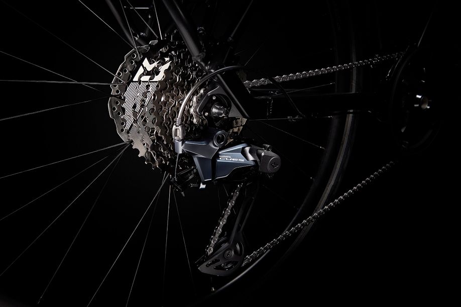 Shimano CUES achterderailleur en cassette met Linkglide technologie op een zwarte fiets met zwarte achtergrond