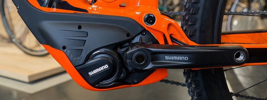 Close-up van de Shimano Steps E8000 middenmotor op een rood/oranje Focus mountainbike in de showroom van 12GO Biking