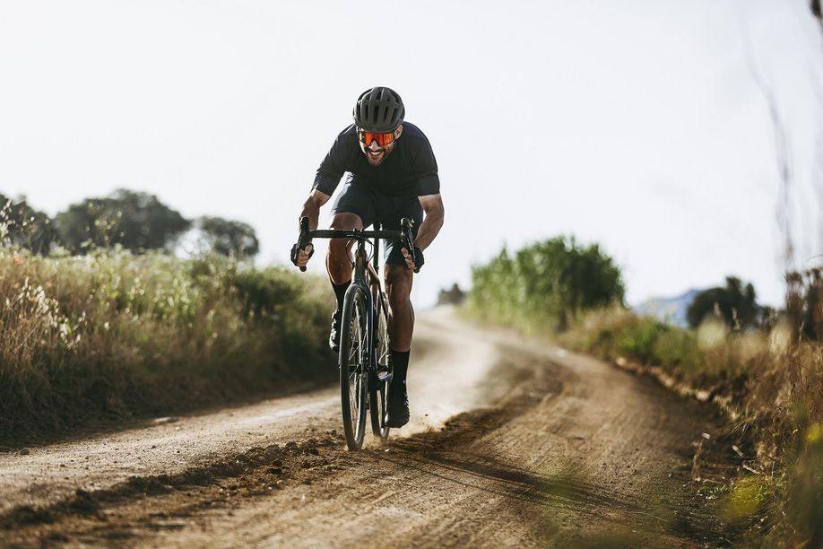 Mannelijke fietser met gravelbike over onverharde weg met stof