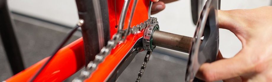 Persoon haalt rechter Ultegra crankarm met trapas uit de trapaslager