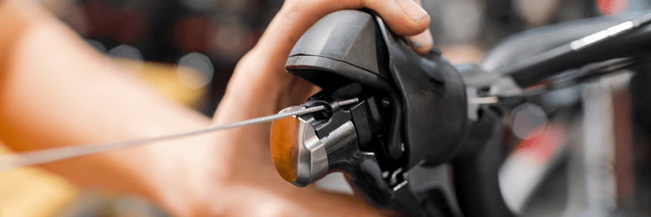 Persoon vervangt de remkabel van een mechanische shifter op de racefiets door de hendel in de drukken