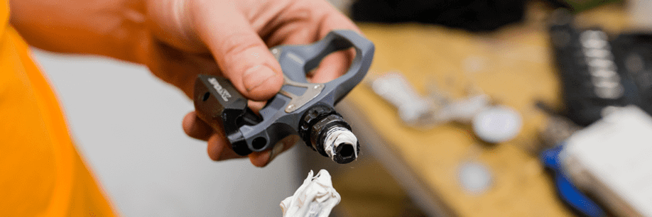 Persoon stopt montagevet op schroefdraad van Shimano SPD SL pedaal 