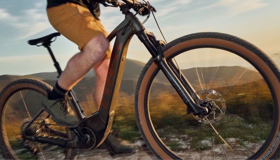 Mountainbiker is staand aan het trappen op een Trek e-mtb op een trail in de bergen