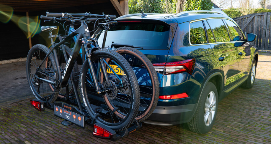 De Spinder TX2 fietsendrager met twee fietsen gemonteerd achterop een auto in een tuin