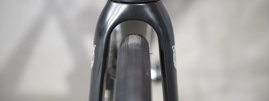 Fietser op Trek Domane racefiets op een kasseien/gravelpad met een setje gravelbanden eronder door de grote ruimte voor brede banden