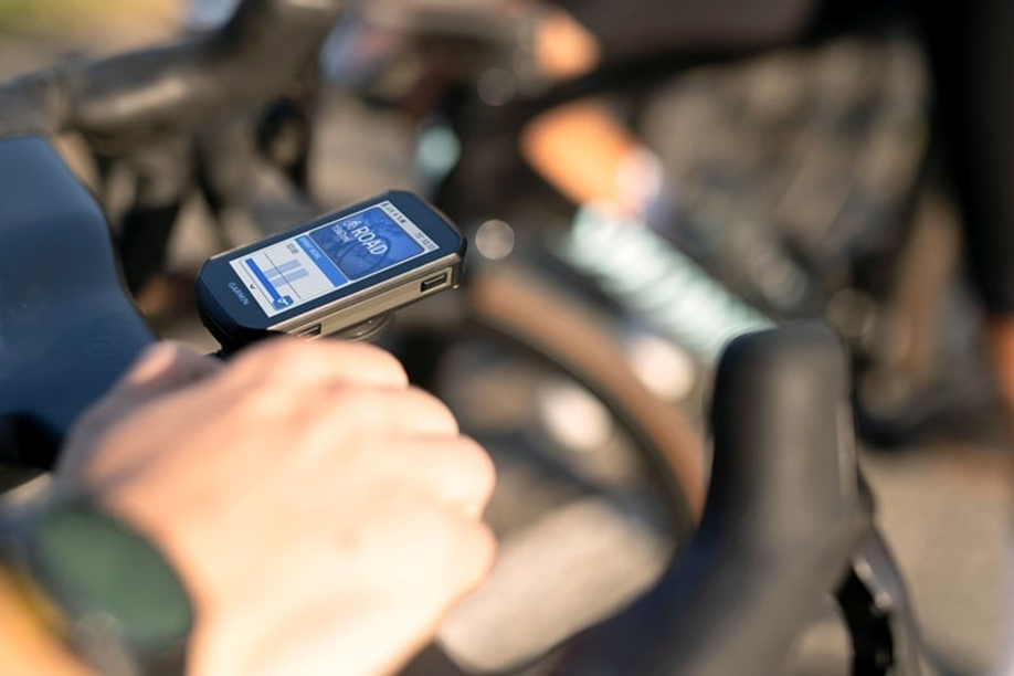 Garmin Edge fietscomputer met 'Road' fietsprofiel gemonteerd op racefietsstuur met hand