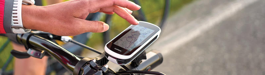 Persoon bedient met hand de Garmin Edge Explore 2 fietscomputer met navigatie op een geasfalteerde weg