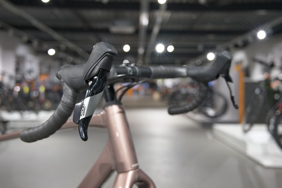 Flared stuur op Trek Checkpoint ALR 5 van schuin vooraf met de showroom van 12GO Biking op de achtergrond