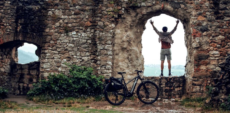 Persoon staand op een muur met een elektrische fiets ervoor