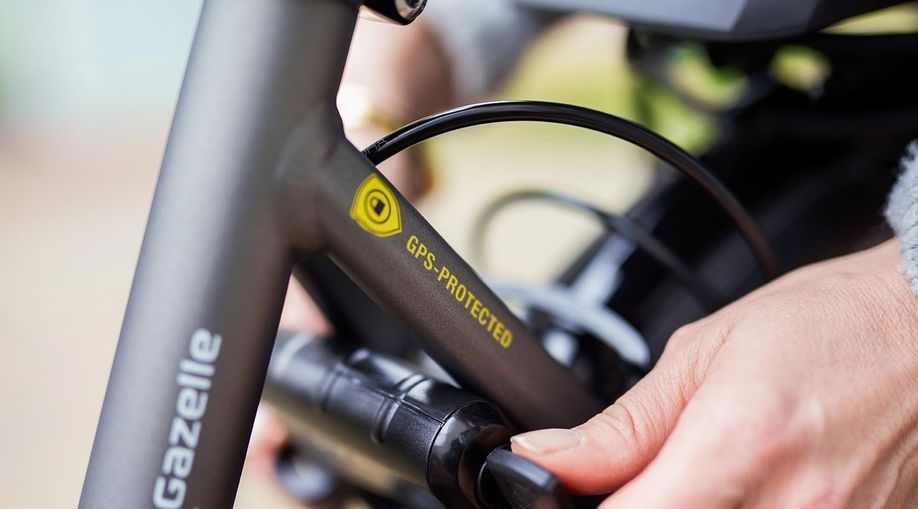 Persoon zet Gazelle fiets met ringslot op slot waarbij de fiets ook voorzien is van een sticker met GPS-Protected