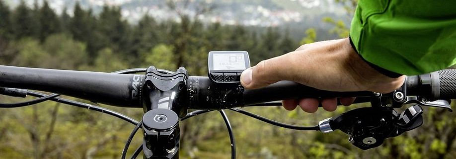 Compacte zwarte fietscomputer met 3 knoppen op MTB-stuur in de bergen