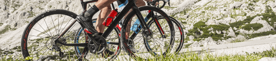 Fietsers op Cube racefietsen die een berg op klimmen over een asfaltweg tussen alle rotsen door