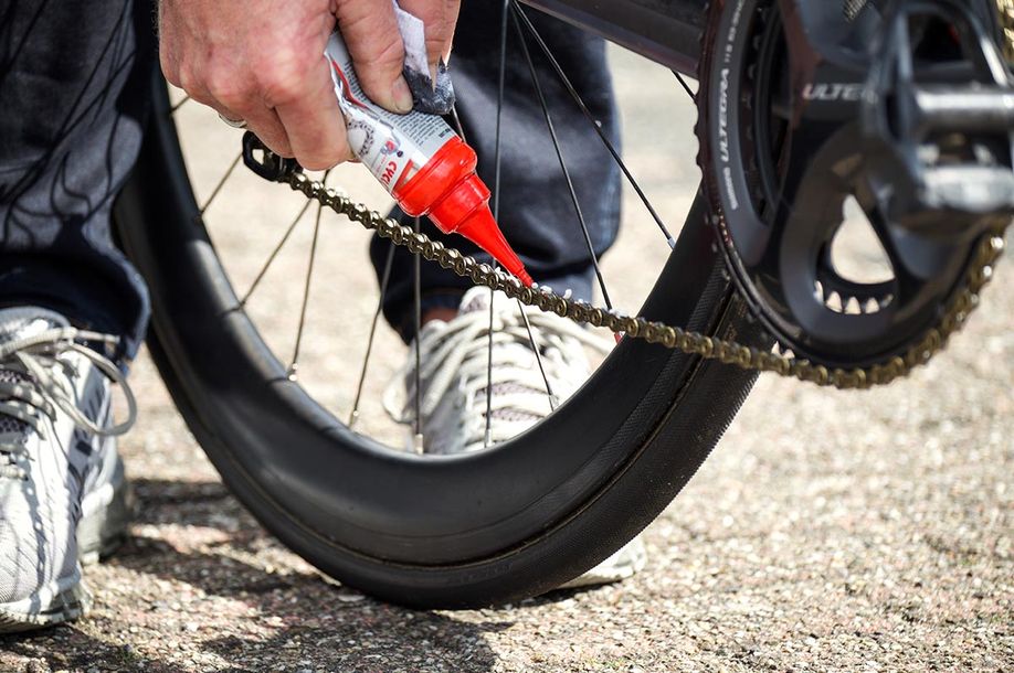 Persoon voegt CyclOn smeermiddel toe aan op de ketting van een racefiets met Ultegra crankstel