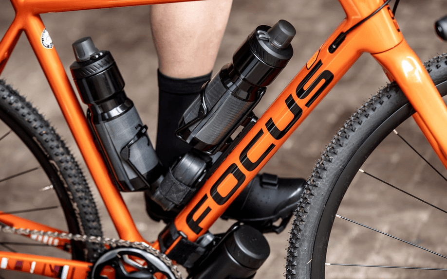 Oranje Focus mountainbike met twee bidons, een tasje en opbergbidon om het frame gemonteerd voor een goede voorziening