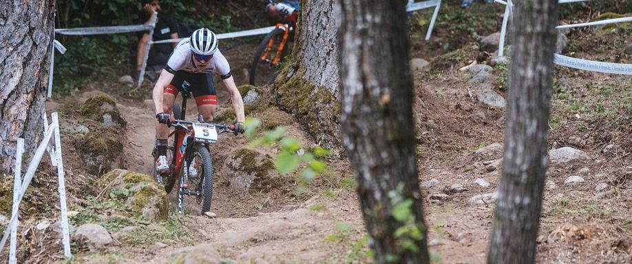 Mountainbikers dalen een technisch bospad af via afgezet parcours voor een wedstrijd